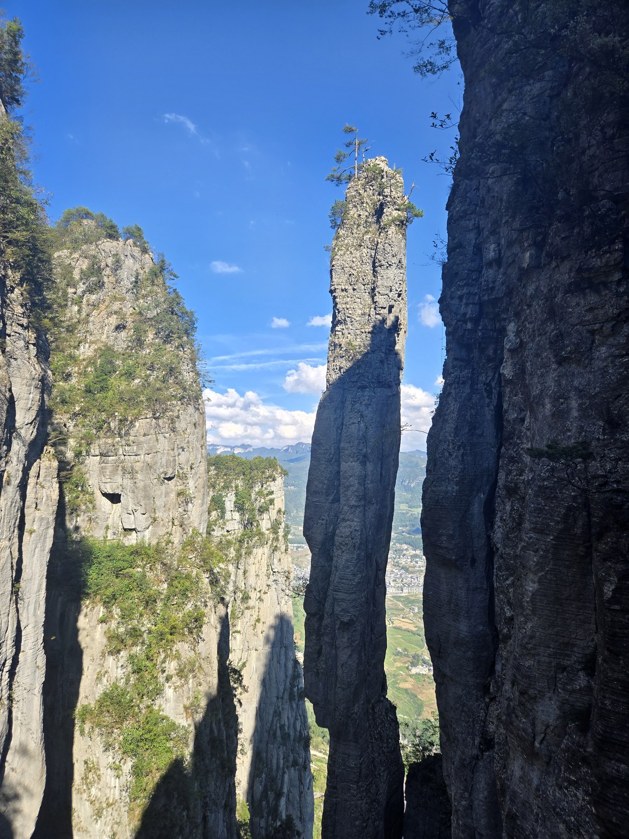 A slender rock pillar rises between high cliffs at Enshi Grand Canyon.