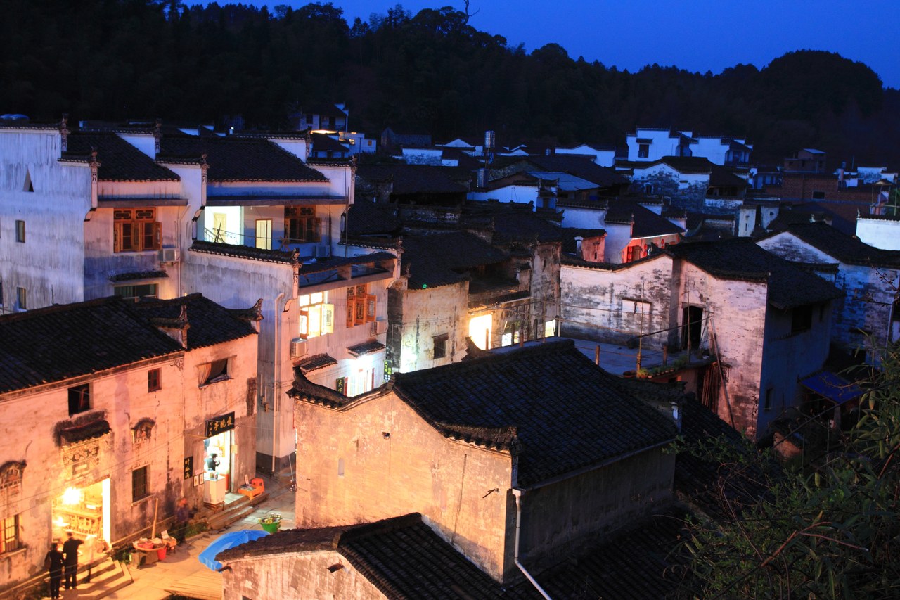 White-walled houses and dark tiled roofs lit at dusk in Likeng village, Qiukou, Wuyuan.