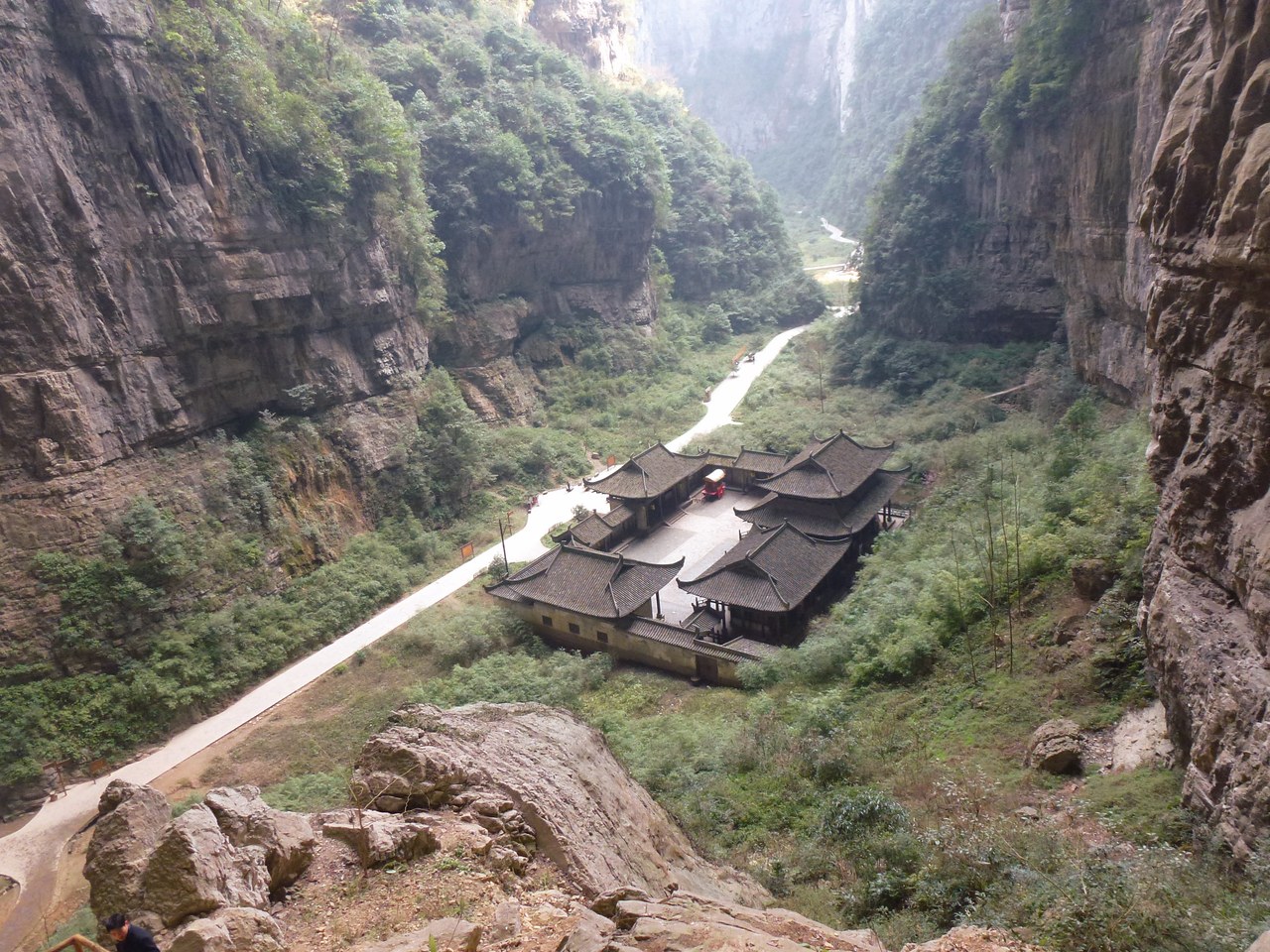 A tiled-roof post-house building on the floor of a deep limestone valley at the Three Natural Bridges in Wulong.