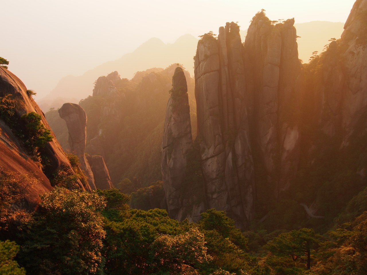 Granite spires at Sanqingshan in warm early-morning light, including the narrow Giant Python rock column.