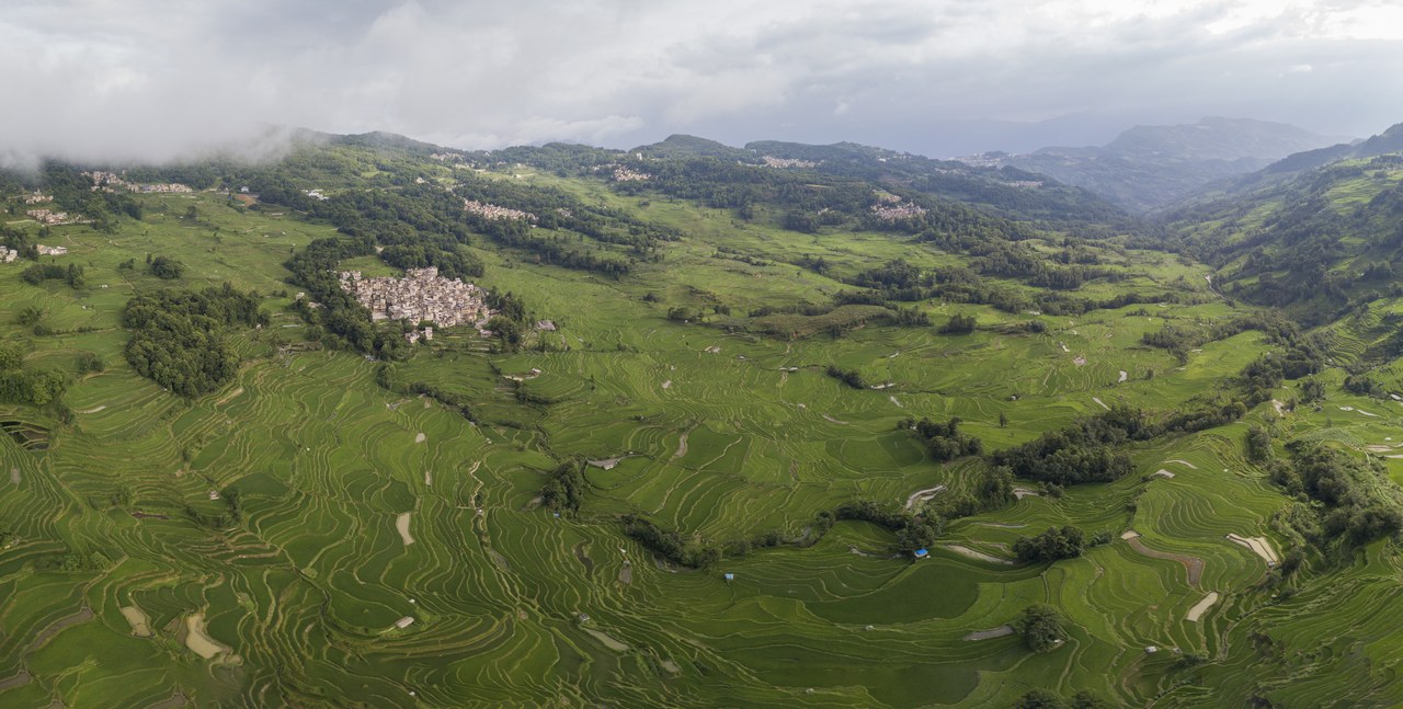 An elevated panorama of green rice terraces, villages and hills in the Bada area of Yuanyang.