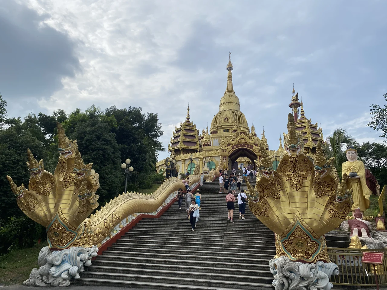 The gold-coloured Menghuan Golden Pagoda above its broad stairway and ornate naga balustrades in Mangshi.
