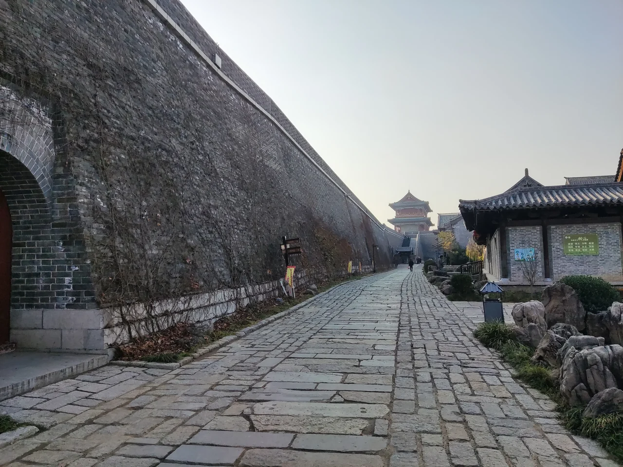 The stone lane beside the southern wall of Qingzhou Ancient City, with tiled buildings and a gate tower ahead.