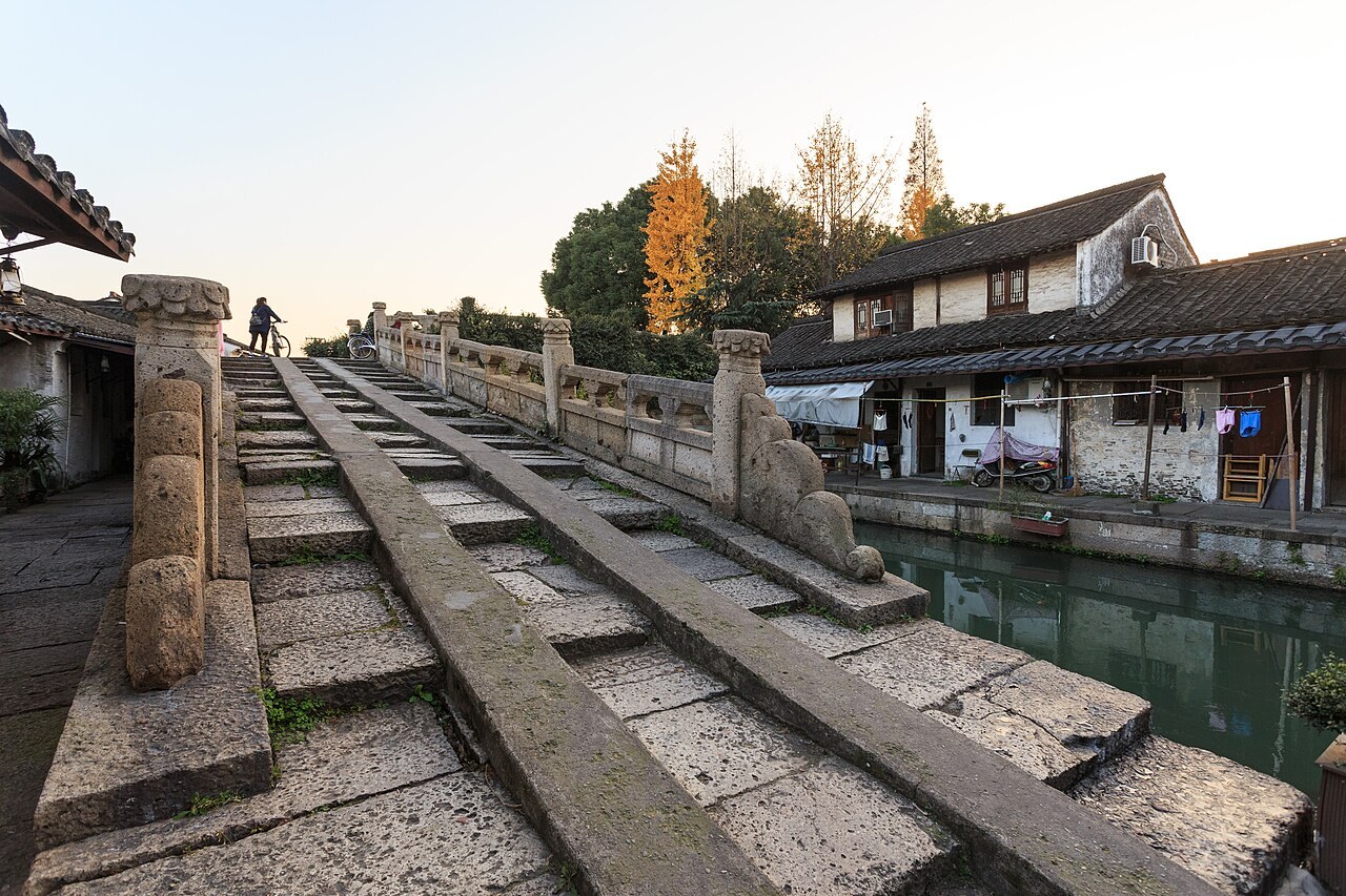 Stone steps of Bazi Bridge rise beside a Shaoxing canal and whitewashed houses.