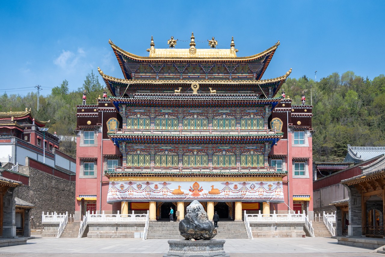 A richly decorated temple facade with a gold roof at Kumbum Monastery.