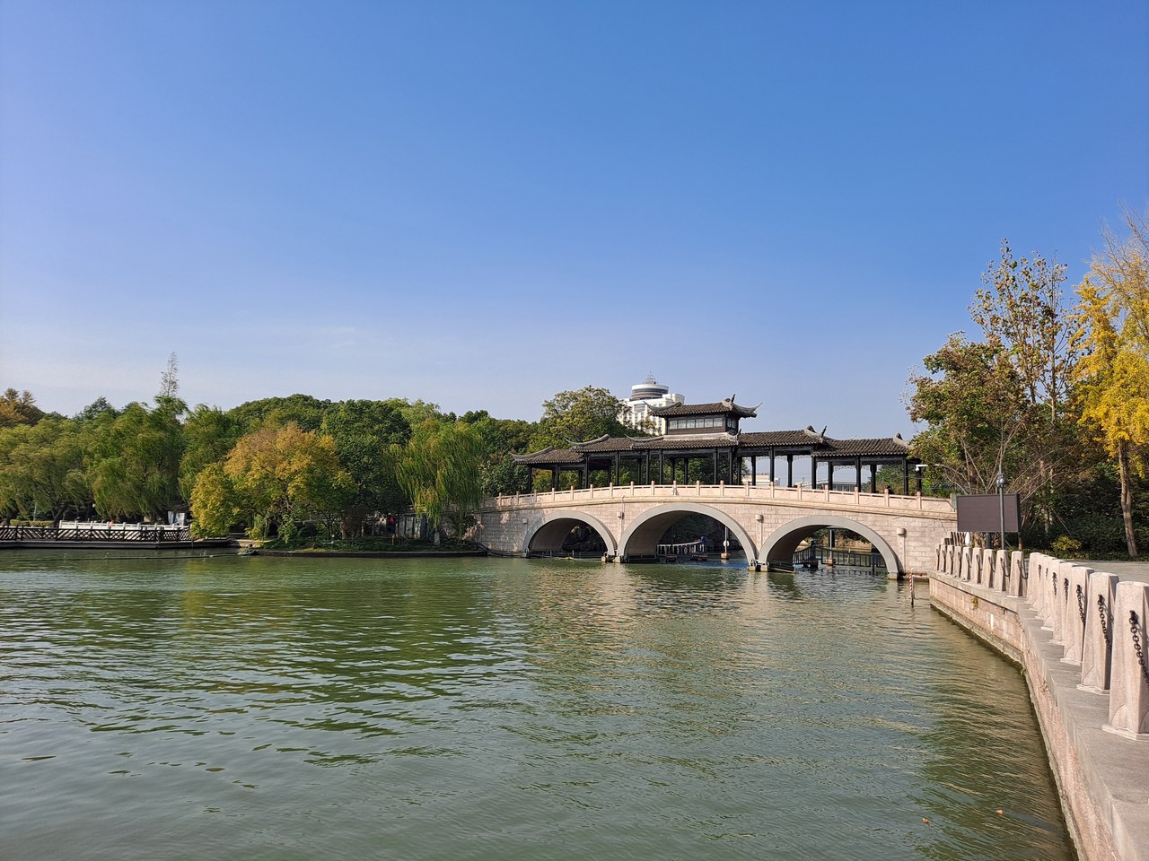 A covered bridge and leafy shore at South Lake in Jiaxing.