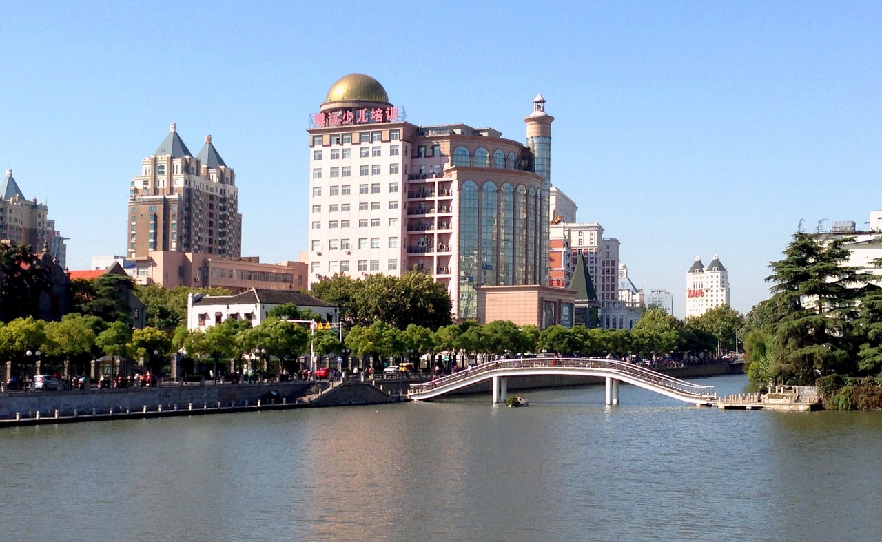 A bridge, trees and city buildings around the Hao River in Nantong.
