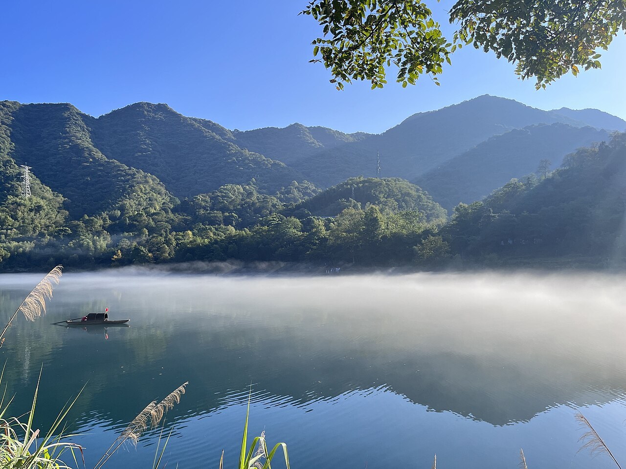 Low mist over Xiaodongjiang’s water beneath wooded hills near Zixing.