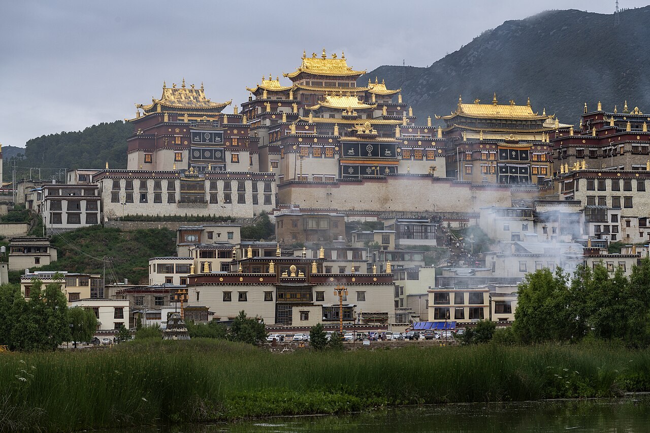 The golden roofs and hillside buildings of Songzanlin Monastery above greenery.
