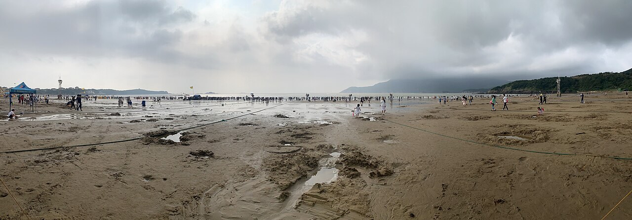 A wide stretch of Nansha beach on Zhujiajian Island, with visitors and the sea.