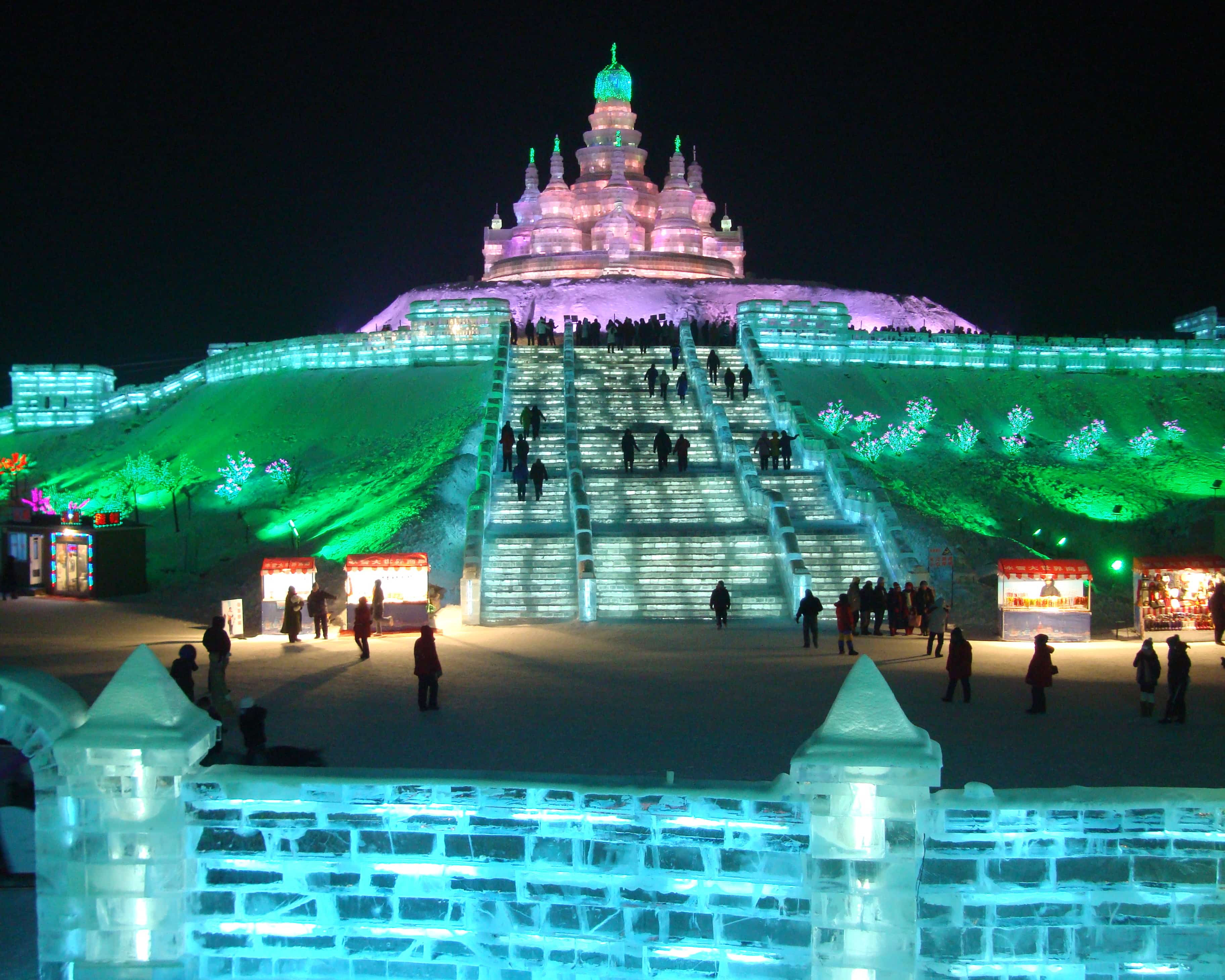 Visitors climb a large illuminated ice structure at a past Harbin Ice and Snow World.