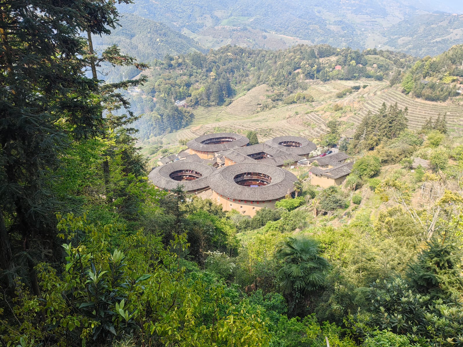 Tianluokeng’s five earthen buildings sit together among terraced hills, seen from above.